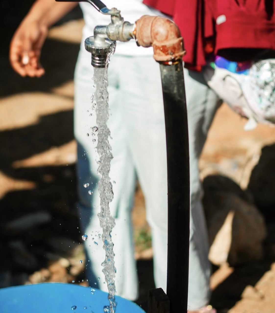 Clean water flowing from a new borehole tap into a blue basin in Lubumbashi, DRC